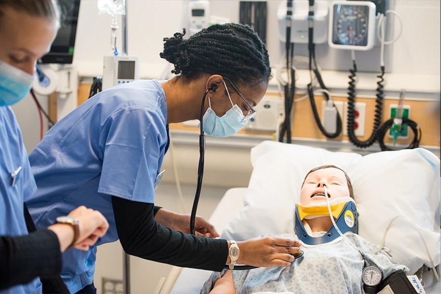 Nursing student treats dummy in simulation lab.